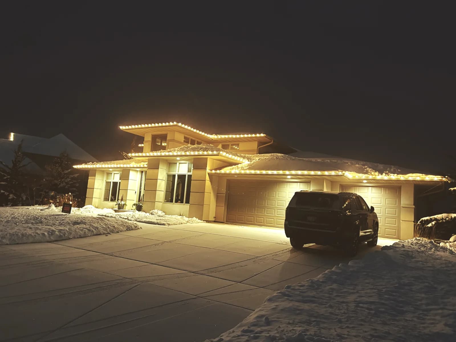 Real Kussmaul Co. permanent lighting in warm white on a modern home with snow on the roof and driveway