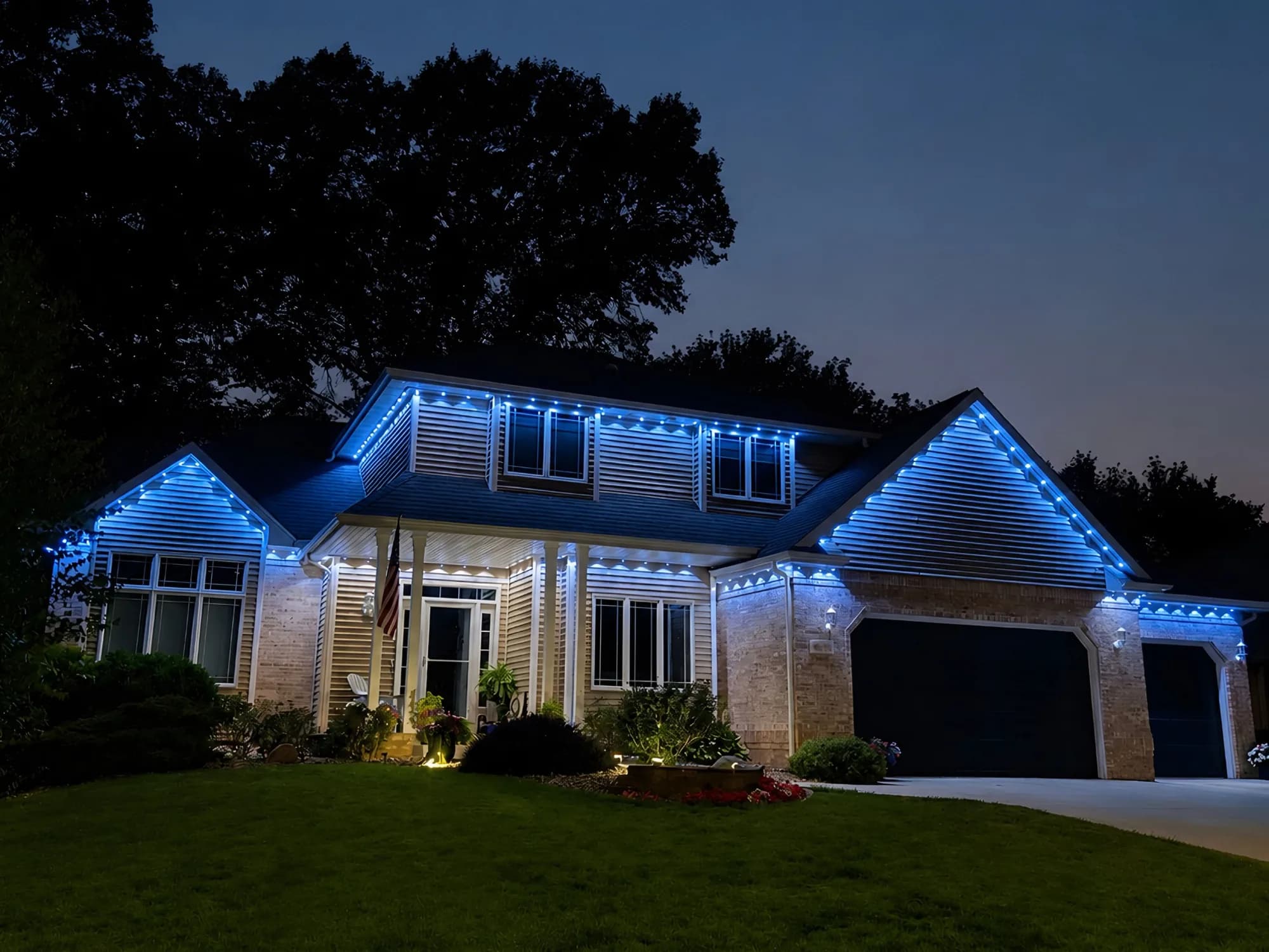 Real Kussmaul Co. permanent lighting running a blue and white scene across a two-story home with a stone front