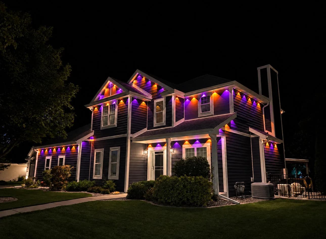 Real Kussmaul Co. permanent lighting running a purple and orange Halloween scene across a two-story home